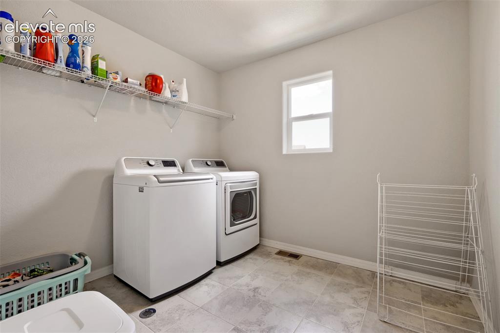 Image 28 of 33: Laundry area with light-toned wall paint and tiled flooring