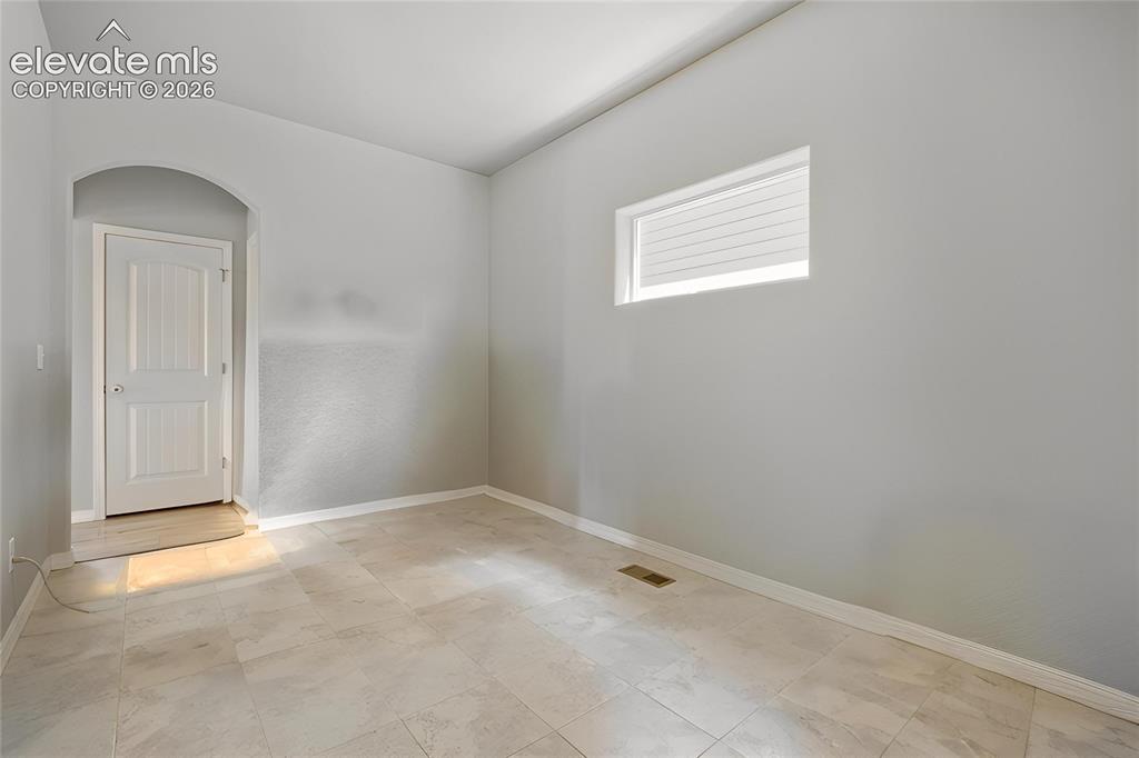 Image 5 of 33: Mudroom off of garage being used as an office featuring light-toned tile f