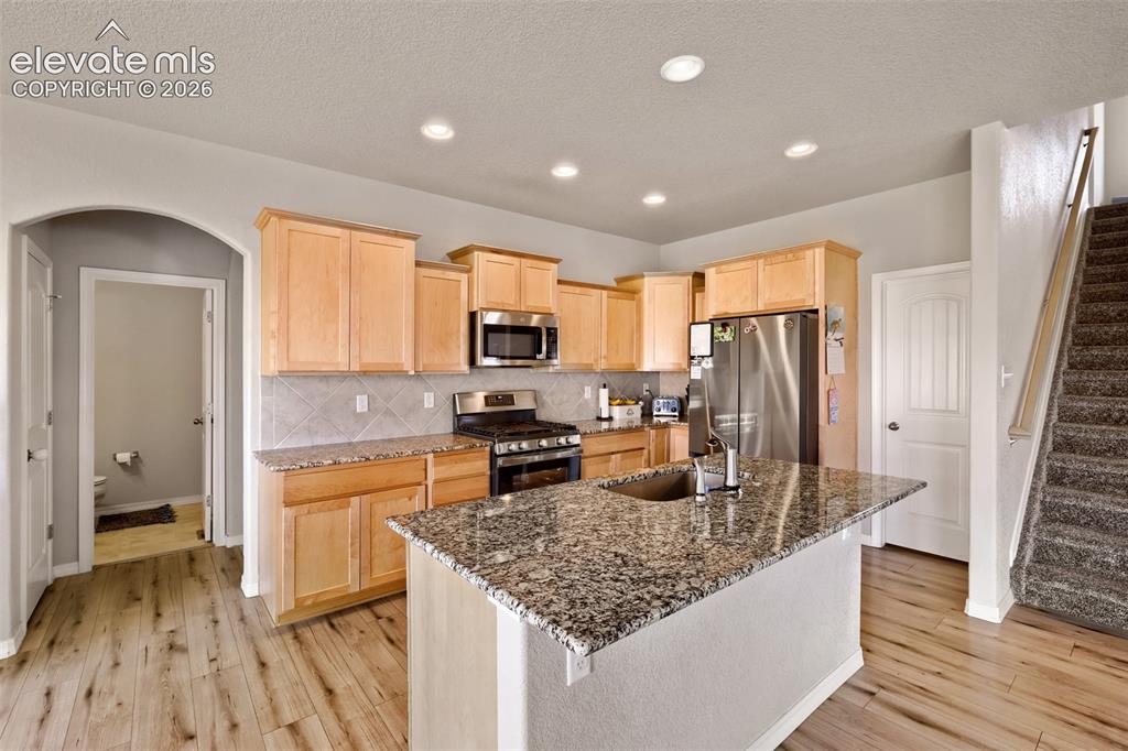 Image 8 of 33: Kitchen featuring wood-finish flooring, a central island with an undermount