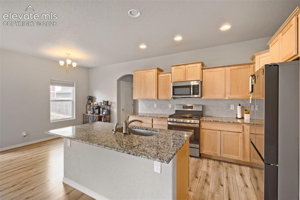 Image 9 of 33: Kitchen featuring a central island with an undermount sink, granite counter