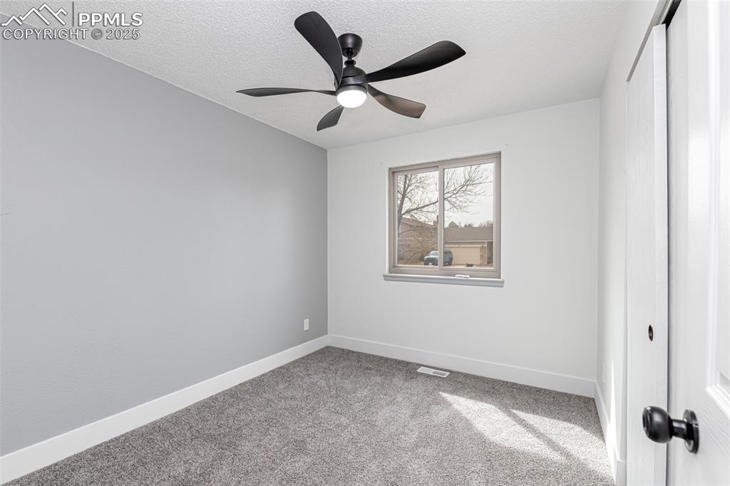 Image 18 of 33: Unfurnished bedroom with light carpet, a ceiling fan, a textured ceiling, a