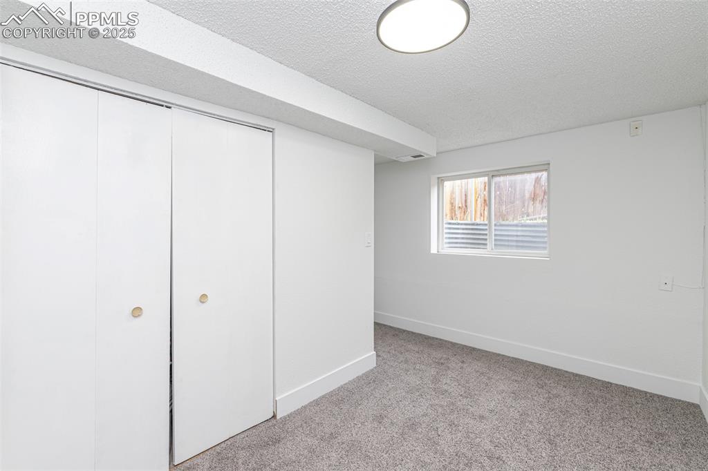 Image 23 of 33: Unfurnished bedroom featuring light carpet, a closet, and a textured ceilin
