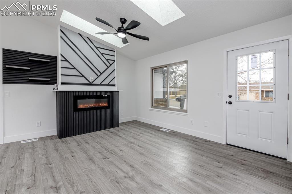 Image 5 of 33: Unfurnished living room featuring lofted ceiling, light wood-style floors, 