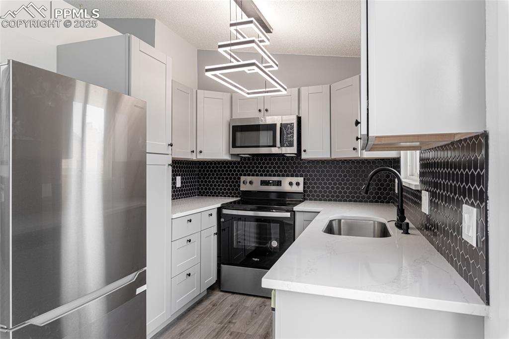 Image 9 of 33: Kitchen featuring appliances with stainless steel finishes, light stone cou