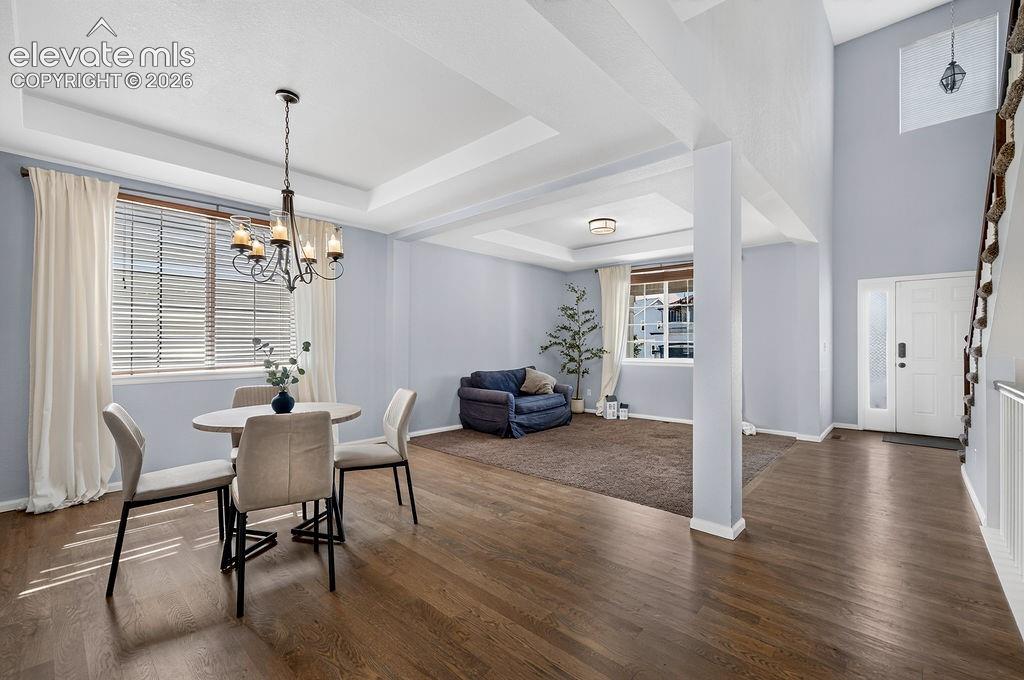 Image 13 of 50: Hardwood-finish flooring throughout, tray ceiling with chandelier, and a tw