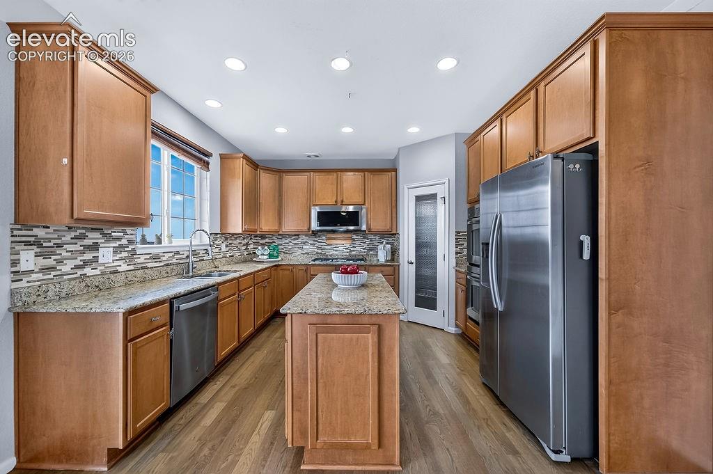 Image 14 of 50: Wood-finish flooring, recessed lighting, wood cabinetry, stainless steel ap