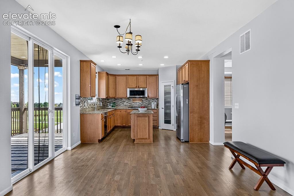 Image 15 of 50: Open-concept kitchen with wood-finish flooring, custom cabinetry, stainless
