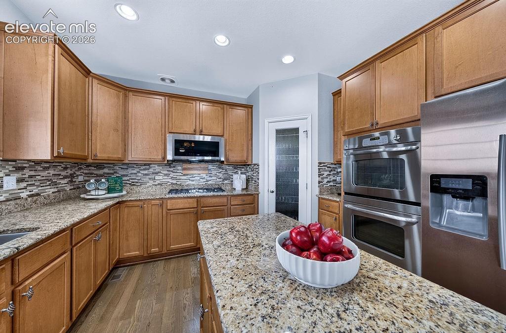 Image 16 of 50: Kitchen featuring abundant wood-finish cabinetry, granite countertops, a mo