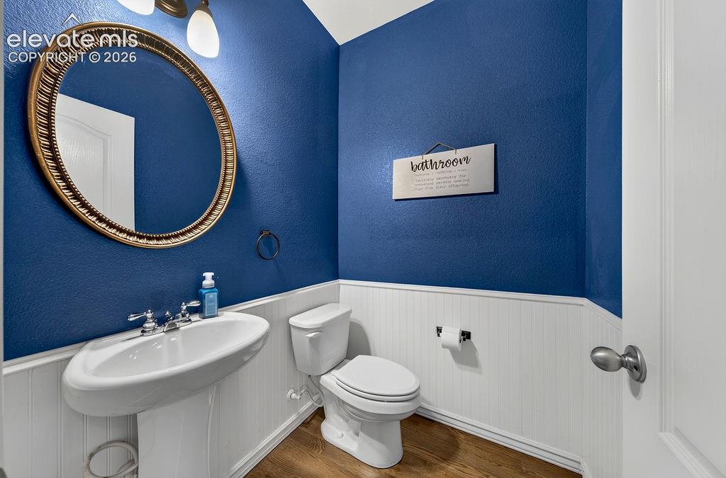 Image 20 of 50: Pedestal sink with chrome fixtures, oval framed mirror, and wood-finish flo
