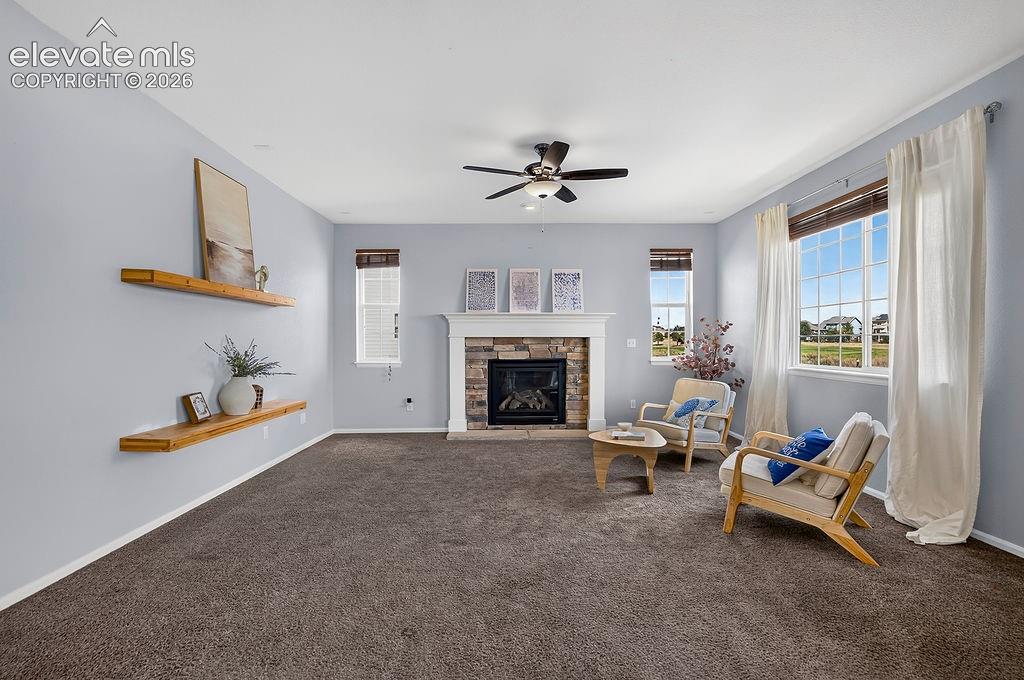 Image 22 of 50: Stone-faced fireplace with a white mantel, ceiling fan with integrated ligh