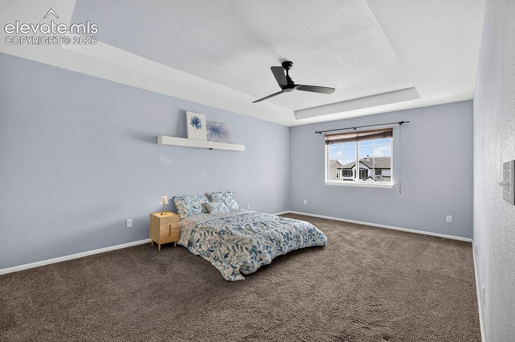 Image 25 of 50: Tray ceiling with recessed lighting, ceiling fan, window with blinds, and w