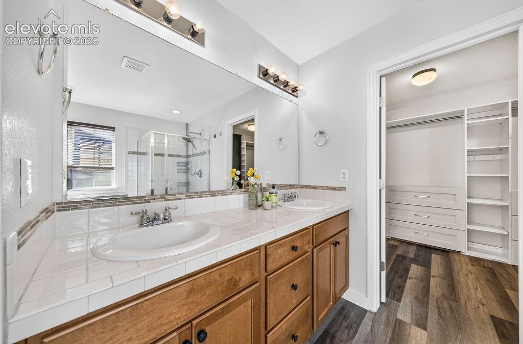 Image 29 of 50: Dual vanity with tile countertops and wood cabinetry