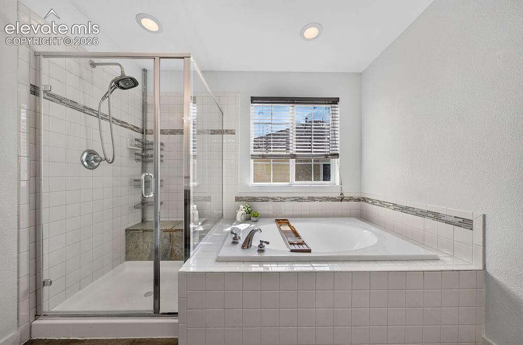 Image 31 of 50: Glass-enclosed shower with a built-in bench, accompanied by a spacious soak