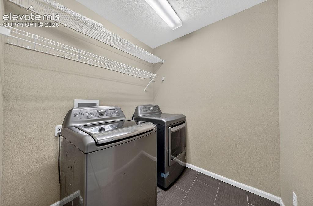 Image 35 of 50: Dedicated laundry area featuring tile flooring and wire shelving