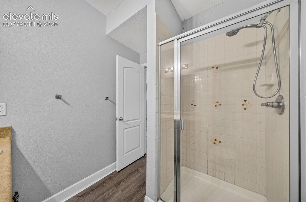 Image 41 of 50: Glass-enclosed shower with a tiled surround, handheld shower fixture, and b