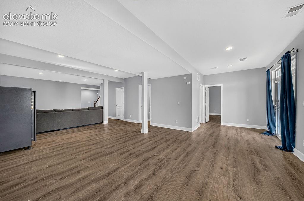 Image 42 of 50: Spacious room featuring wood-finish flooring, recessed lighting, and light