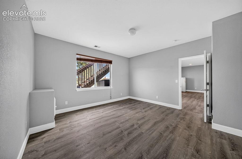 Image 43 of 50: Wood-finish flooring, neutral gray wall tones, window with a wood-tone blin