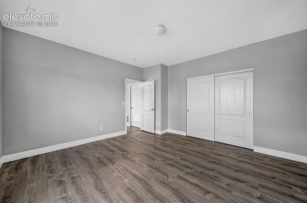 Image 44 of 50: Wood-finish flooring, light gray walls, white trim, white paneled doors, an