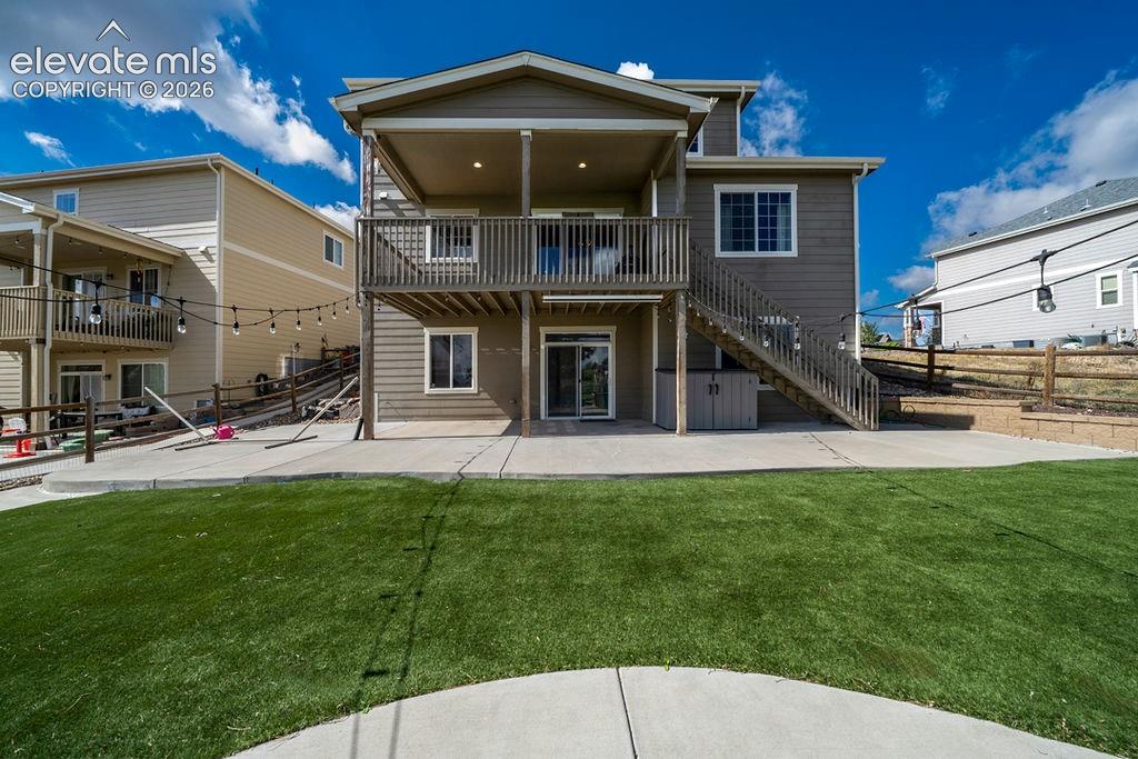 Image 9 of 50: Expansive artificial turf lawn with a concrete patio, wood deck, and walk-o