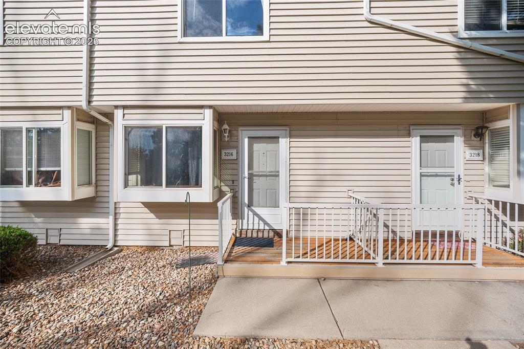 Caption: Vinyl siding exterior with a front porch, white railings, and bay windows
