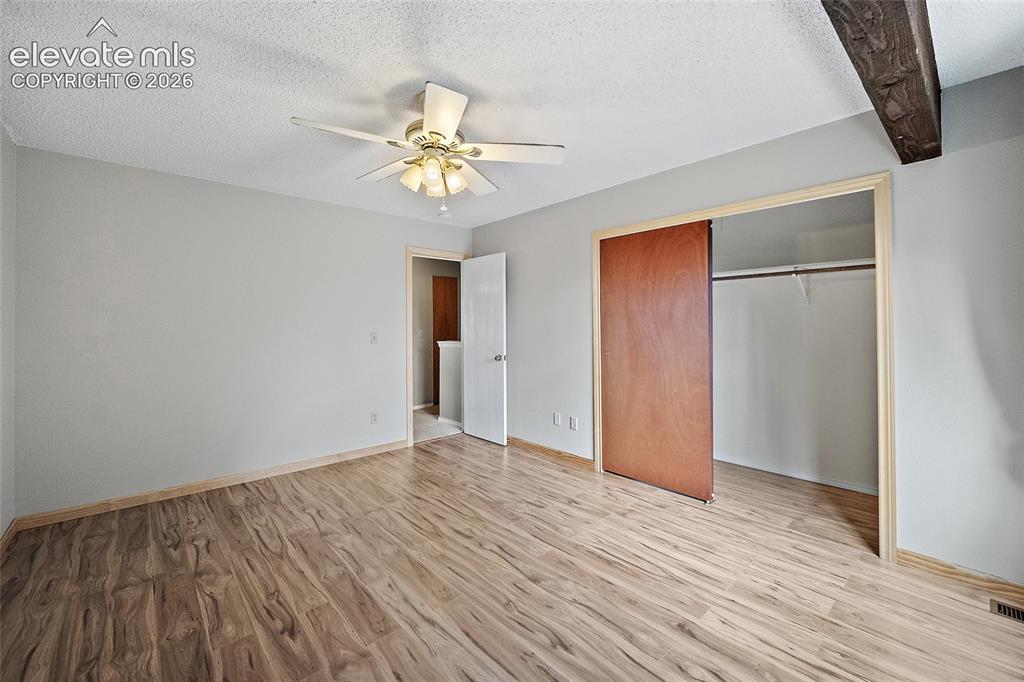 Image 12 of 29: Wood-finish flooring with coordinating wood trim, sliding wood closet door,