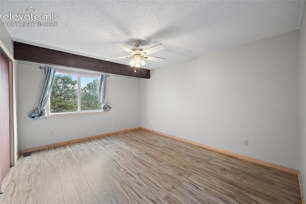 Image 16 of 29: Wood-finish flooring, corner fireplace with tile surround and wood mantel, 
