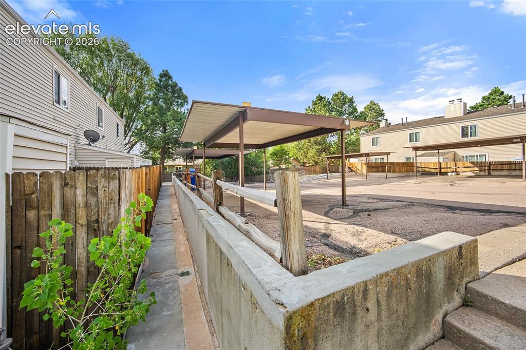Image 23 of 29: Detached storage shed with paneled door, wood privacy fencing, and concrete