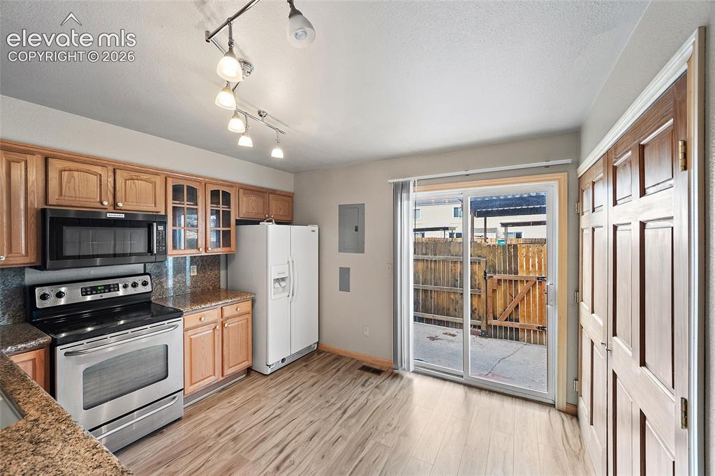 Image 6 of 29: Wood-finish flooring, light wood cabinetry, stone countertops, stainless st