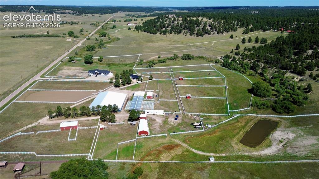 Caption: Expansive property featuring multiple outbuildings, fenced paddocks, a large barn, an arena, and a p