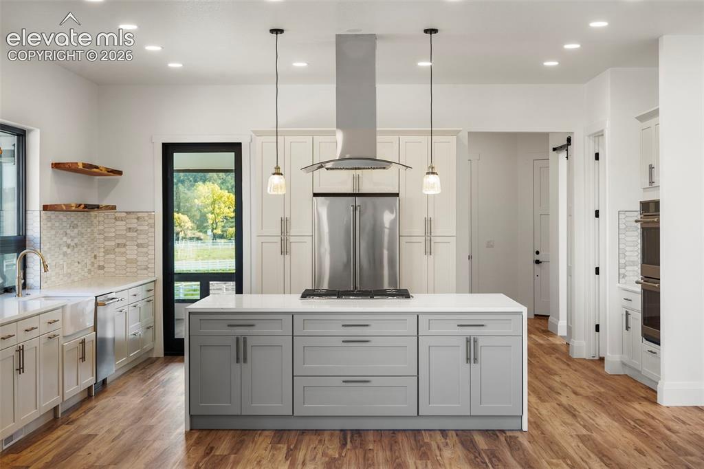 Image 11 of 41: Kitchen featuring wood-finish flooring, a central island with integrated co