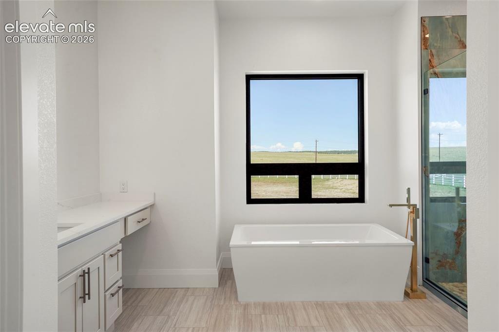 Image 13 of 41: Freestanding soaking tub with a floor-mounted gold-tone faucet, large black
