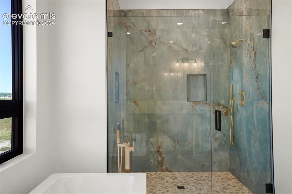 Image 14 of 41: Walk-in shower with clear glass enclosure and stone-look tile