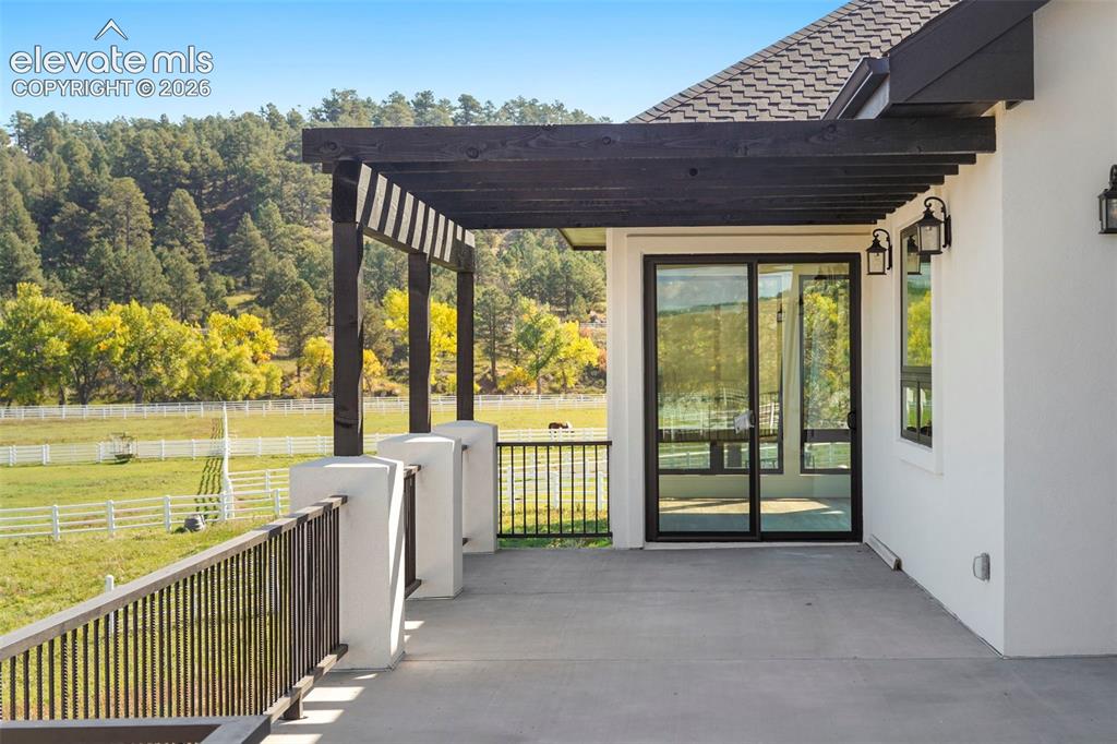 Image 16 of 41: Spacious outdoor patio with dark wood pergola, black metal railings, and du