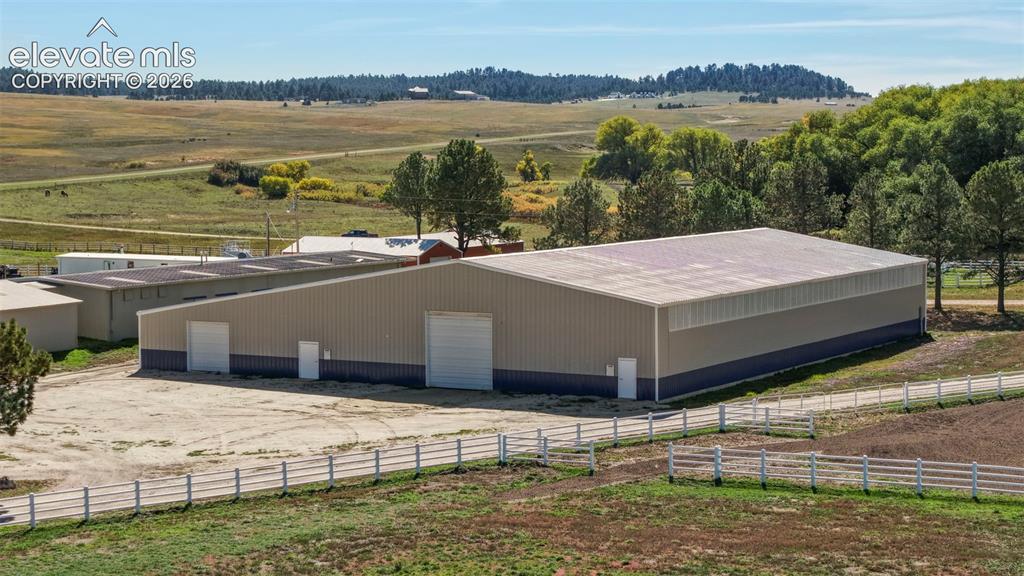 Image 18 of 41: Arena - Large metal building with multiple access doors, a wide garage door