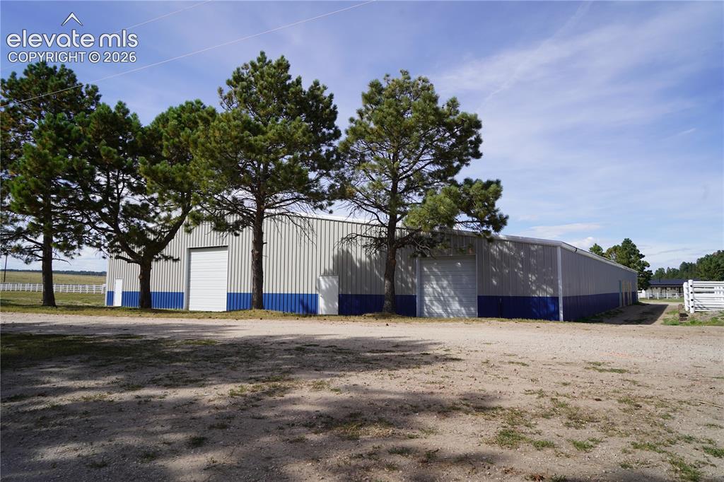 Image 19 of 41: Arena - Expansive metal building featuring a pitched roof, multiple entry d