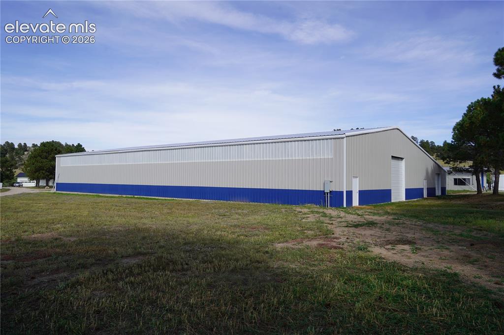 Image 20 of 41: Arena - Expansive metal building featuring a pitched roof, multiple entry d