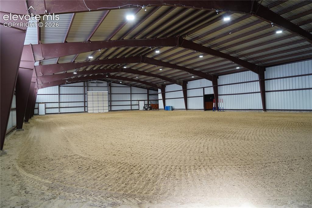 Image 22 of 41: Expansive indoor arena with a sand footing, high ceilings with exposed stee