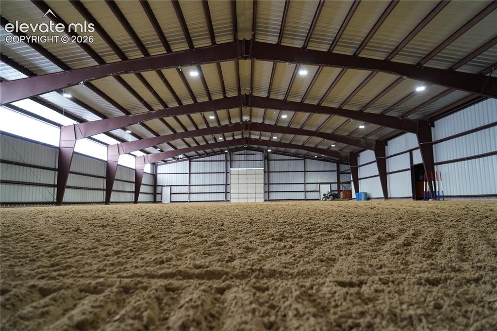 Image 23 of 41: Expansive indoor arena with a sand footing, high ceilings with exposed stee