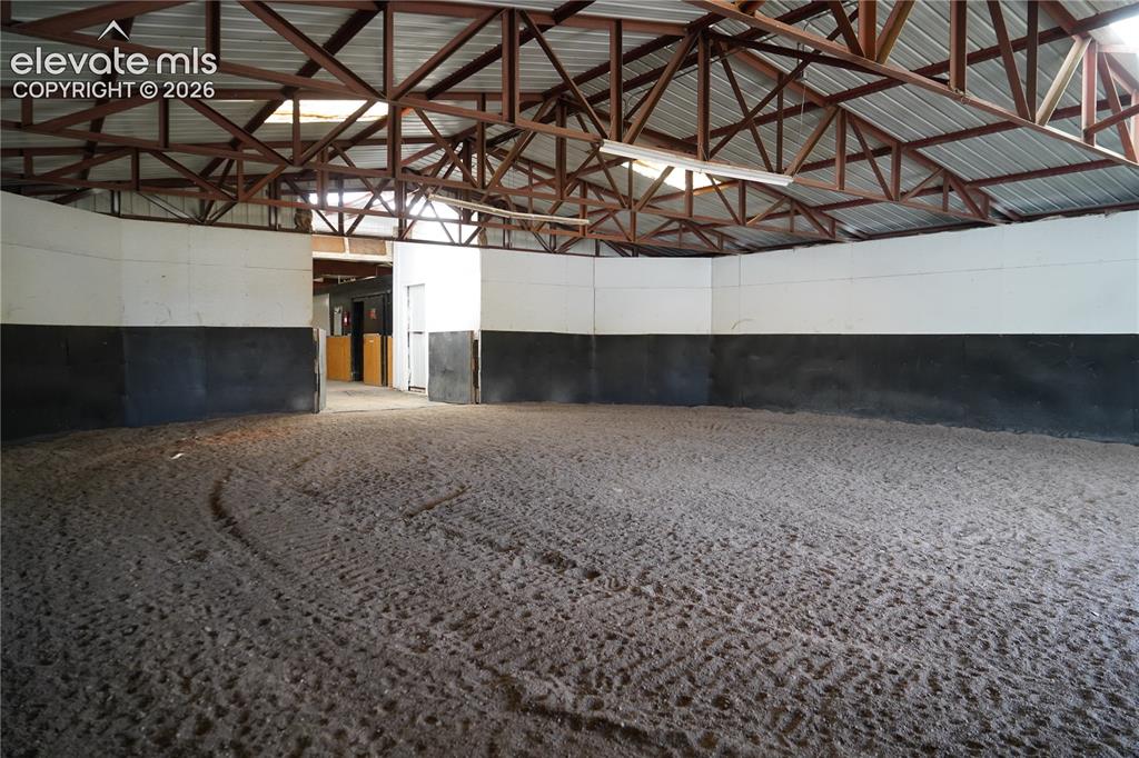 Image 24 of 41: Expansive indoor arena with a sand footing, high ceilings with exposed stee