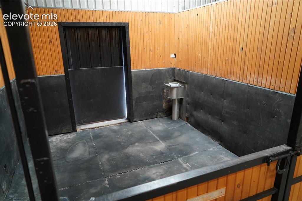 Image 30 of 41: Wood-paneled stall with black-painted lower walls, a built-in water fixture