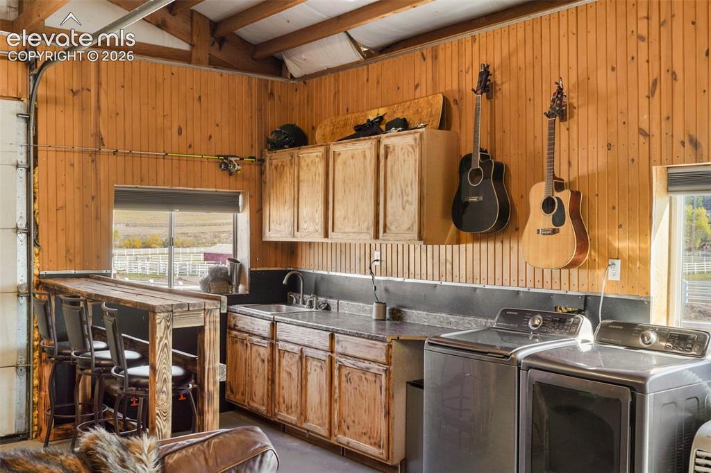 Image 39 of 41: Wood-paneled interior featuring a built-in bar, stainless steel washer and