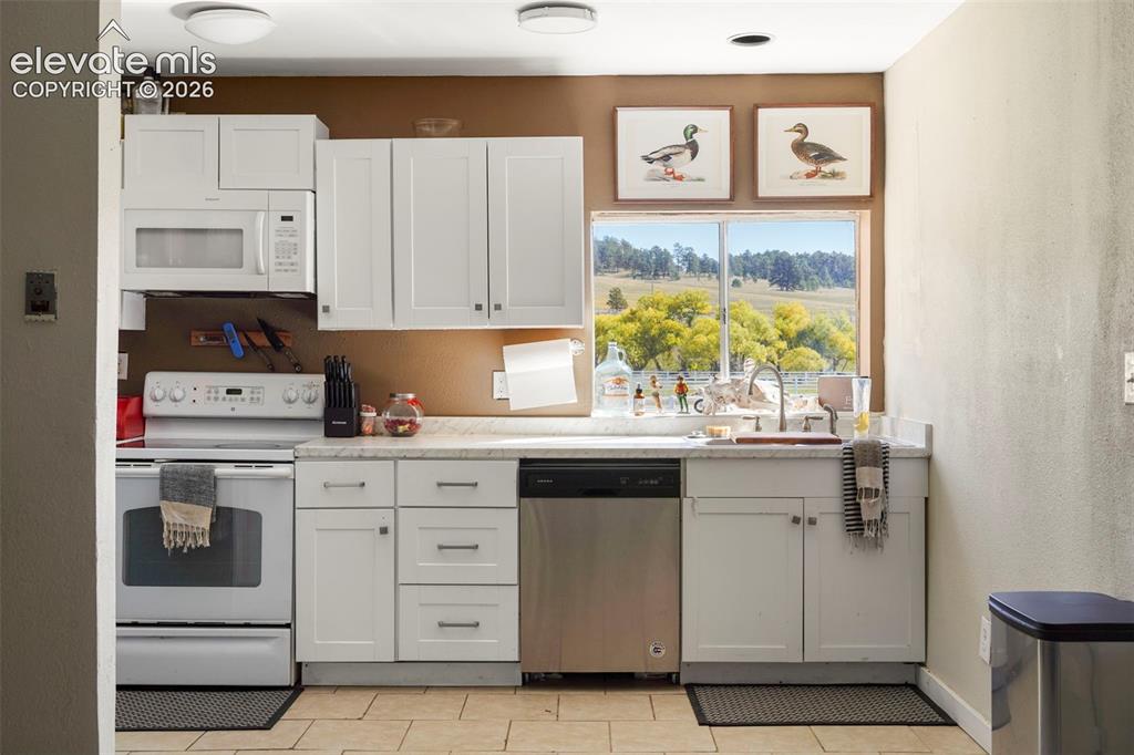 Image 40 of 41: Kitchen featuring white cabinetry, light-toned countertops, a stainless ste