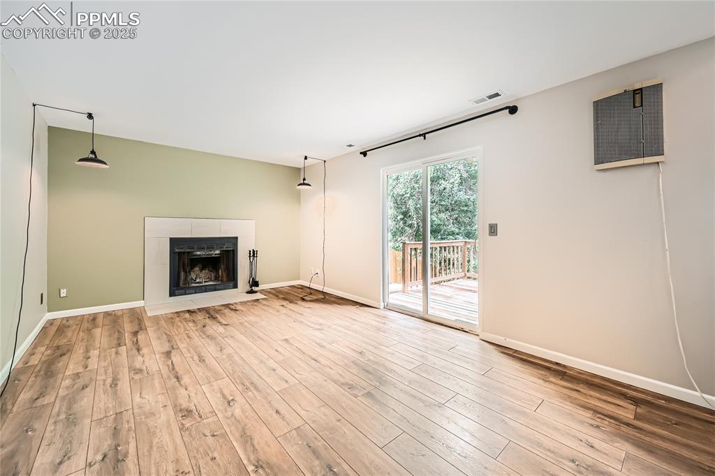Image 22 of 32: Unfurnished living room featuring wood finished floors and a tile fireplace