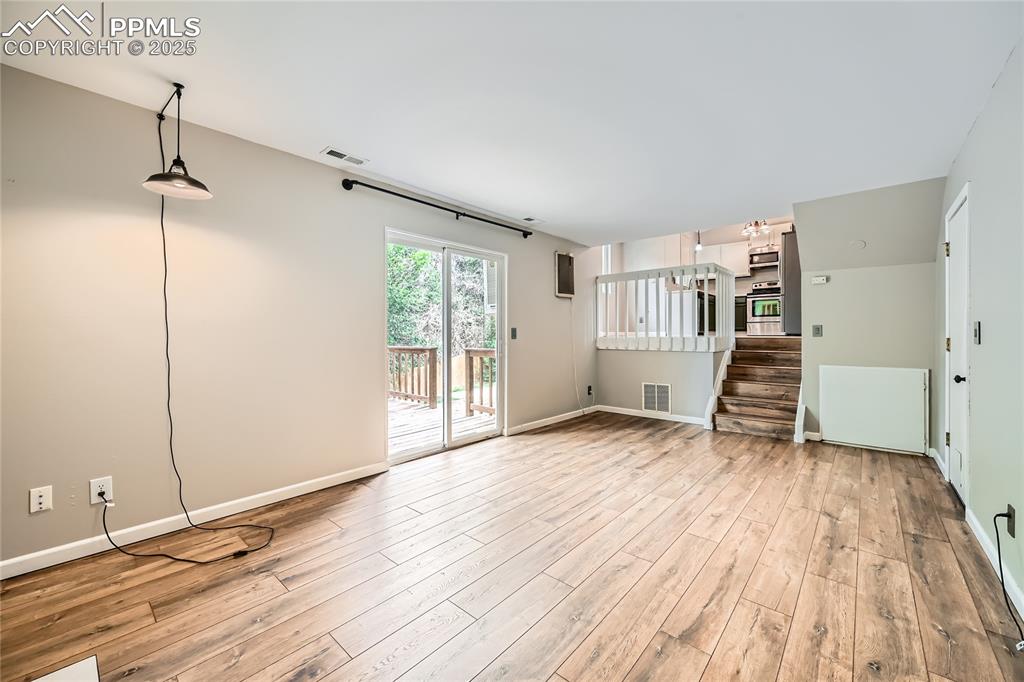 Image 23 of 32: Unfurnished living room featuring wood finished floors and stairway