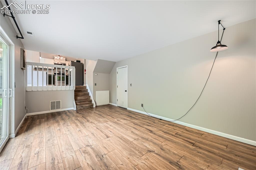 Image 24 of 32: Unfurnished living room with hardwood / wood-style floors and stairs