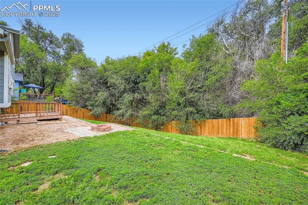 Image 28 of 32: Fenced backyard featuring a fire pit and a deck