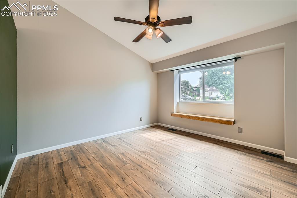 Image 4 of 32: Spare room with lofted ceiling, a ceiling fan, and wood finished floors