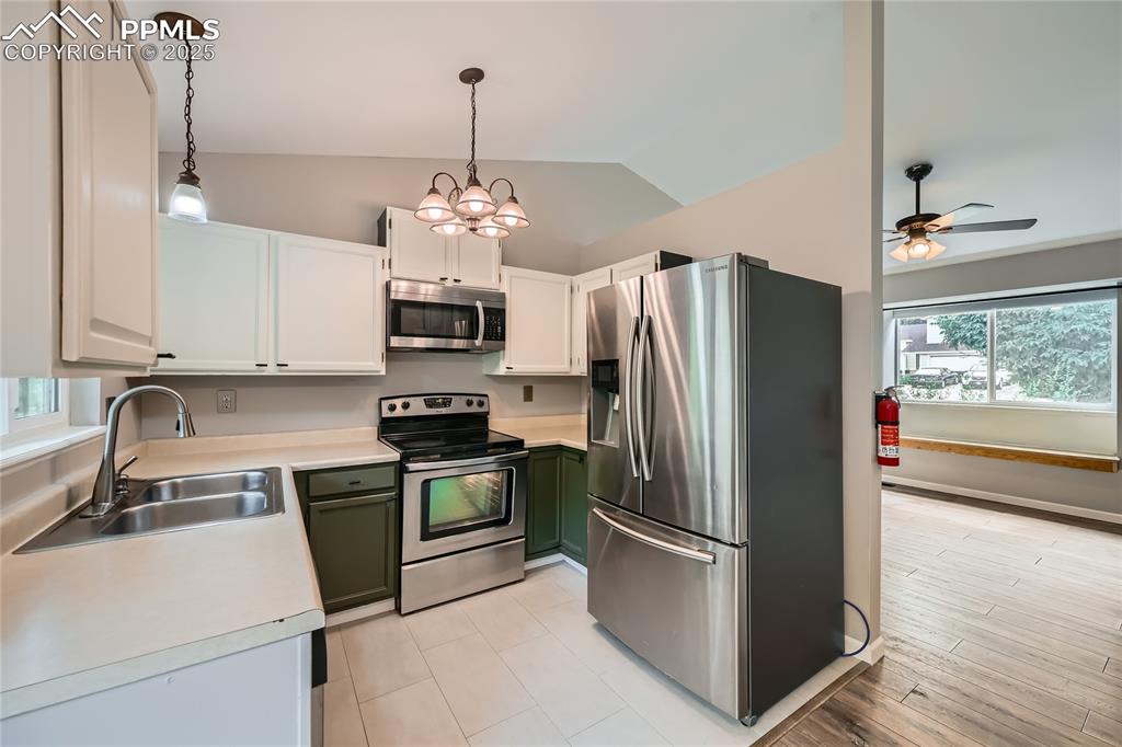Image 8 of 32: Kitchen featuring lofted ceiling, appliances with stainless steel finishes,