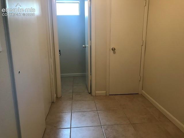 Image 14 of 18: Hallway with square tile flooring, multiple doors, and a transom window