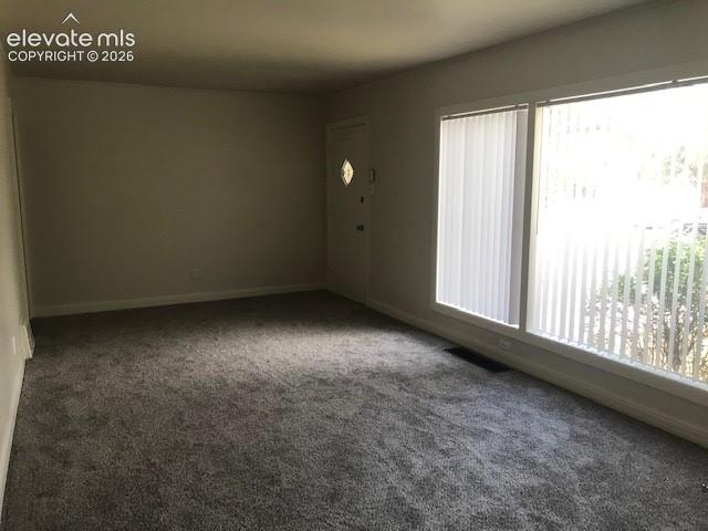 Image 2 of 18: Gray carpeting throughout, white walls, large windows with vertical blinds,